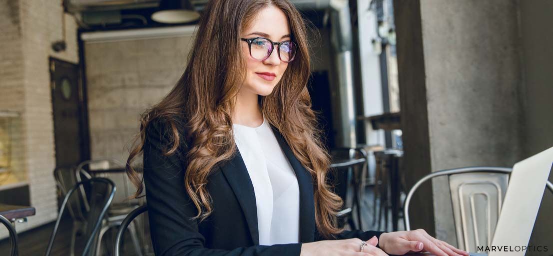 woman wearing glasses in front of computer
