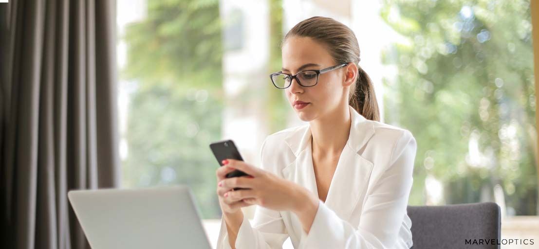 Woman wearing prescription glasses while using her phone