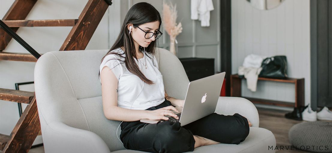 woman wearing blue light glasses in front of her laptop