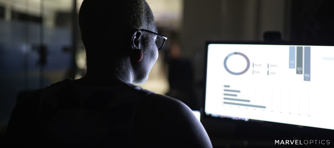 man wearing blue light glasses in front of the screen