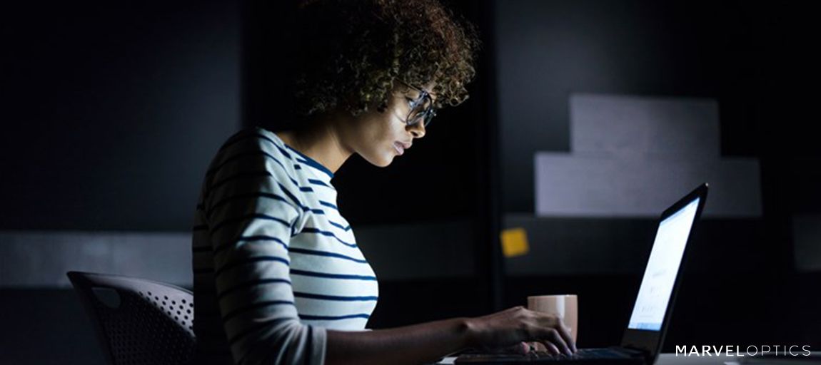 man wearing blue light glasses in front of her laptop